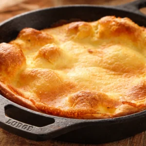 Golden gluten free Dutch baby pancake topped with powdered sugar and lemon juice.