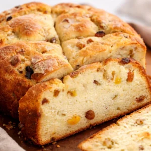 Slice of soft gluten free Irish soda bread with a crispy crust and raisins.