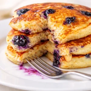 Fluffy gluten-free buttermilk blueberry pancakes topped with fresh blueberries